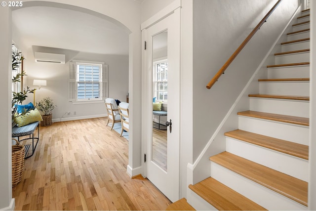 stairway featuring hardwood / wood-style floors and an AC wall unit