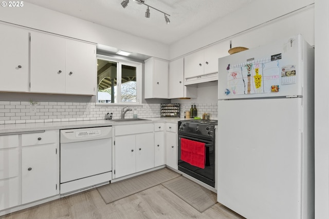 kitchen featuring under cabinet range hood, white appliances, a sink, white cabinets, and light countertops