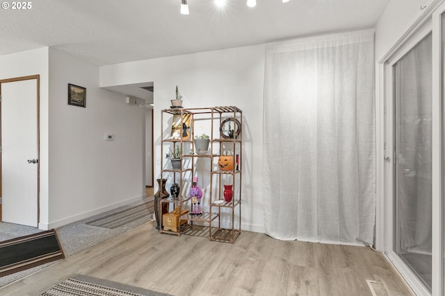 hallway with a textured ceiling, wood finished floors, and baseboards