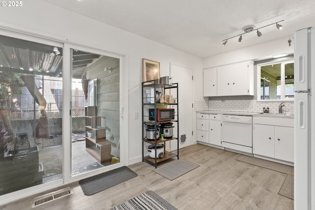 kitchen featuring white appliances, a sink, visible vents, light countertops, and light wood finished floors