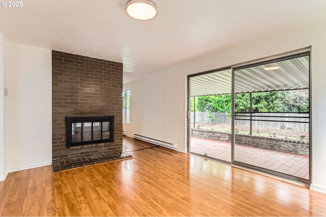 unfurnished living room featuring baseboards, a baseboard heating unit, wood finished floors, and a fireplace