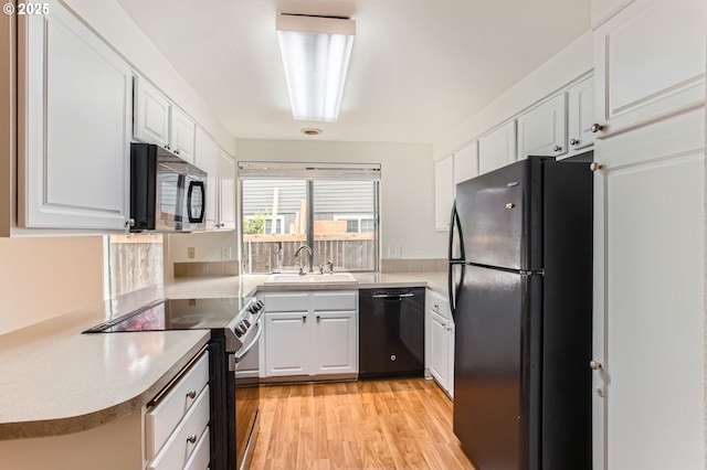 kitchen with light wood-type flooring, light countertops, white cabinets, a sink, and black appliances