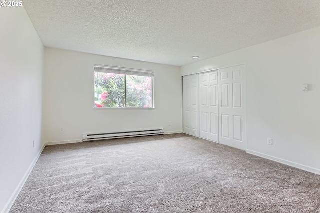 unfurnished bedroom with carpet floors, baseboards, baseboard heating, and a textured ceiling