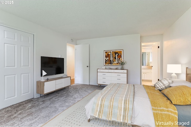 carpeted bedroom featuring a textured ceiling and ensuite bath