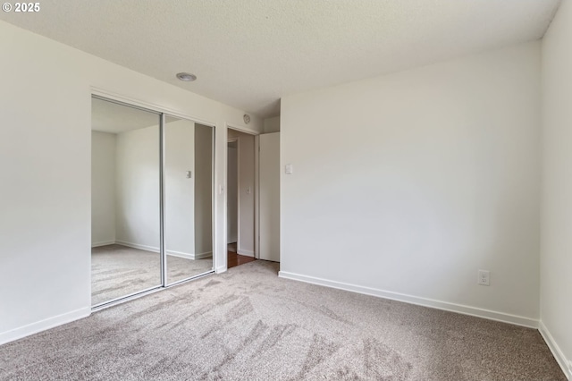 unfurnished bedroom with baseboards, carpet, and a closet