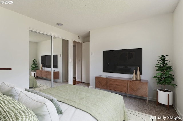 carpeted bedroom featuring baseboards and a closet
