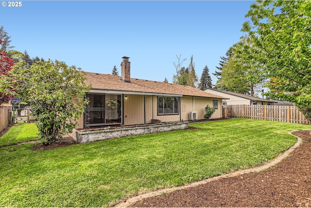rear view of house featuring a fenced backyard, a chimney, and a yard
