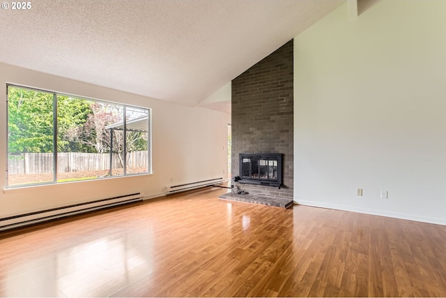 unfurnished living room featuring a textured ceiling, a fireplace, baseboard heating, vaulted ceiling, and wood finished floors