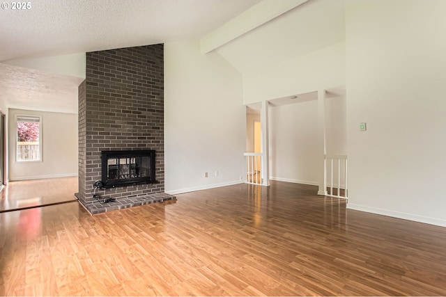 unfurnished living room with baseboards, high vaulted ceiling, wood finished floors, and a fireplace