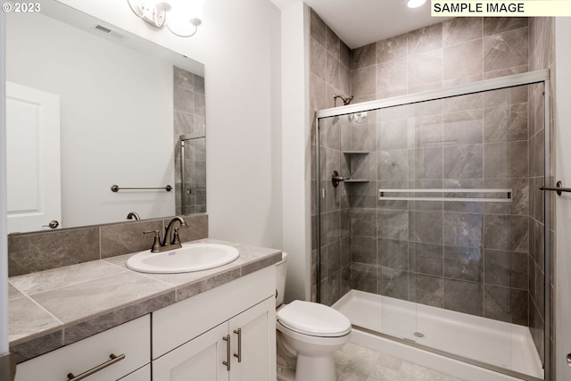 bathroom with toilet, tile floors, vanity, and a shower with shower door