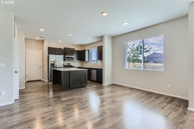 kitchen with a kitchen island, appliances with stainless steel finishes, light countertops, and wood finished floors