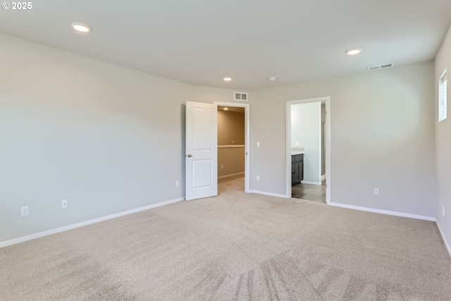 carpeted empty room with baseboards, visible vents, and recessed lighting