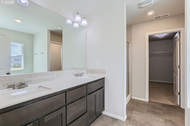 bathroom with a stall shower, a spacious closet, visible vents, and a sink