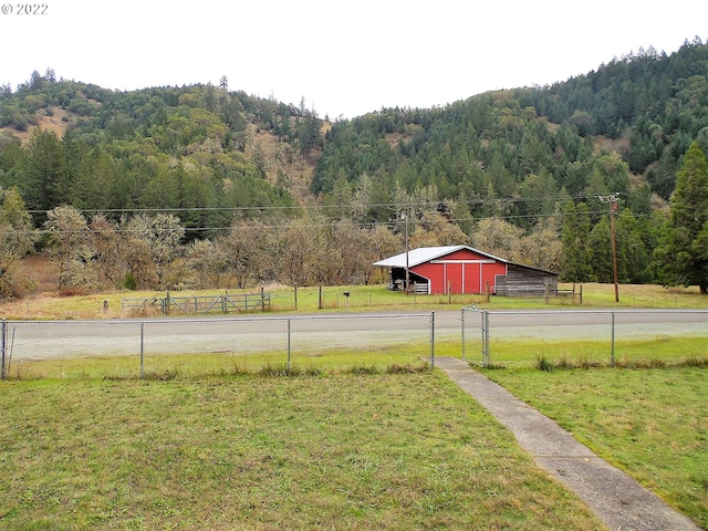 view of yard with an outbuilding, a mountain view, and a rural view