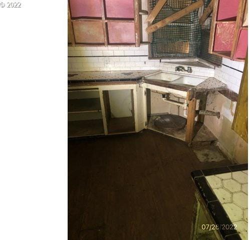 interior space featuring tasteful backsplash, tile countertops, and sink