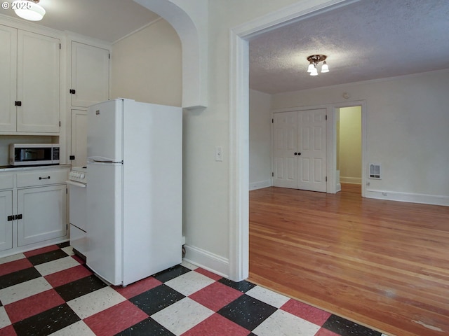 20 NW 16th Ave Unit 211, Portland, OR 97209 - kitchen with freestanding refrigerator, stainless steel microwave, light flooring, white cabinetry, and range