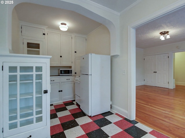 20 NW 16th Ave Unit 211, Portland, OR 97209 - kitchen with freestanding refrigerator, stainless steel microwave, tile patterned floors, and white cabinetry