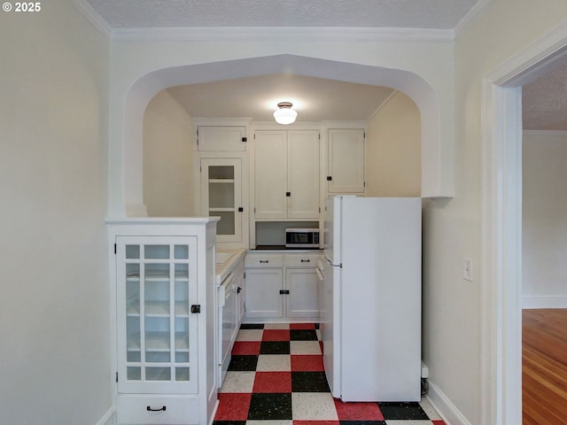 20 NW 16th Ave Unit 211, Portland, OR 97209 - kitchen with freestanding refrigerator, stainless steel microwave, dark flooring, arched walkways, and ornamental molding