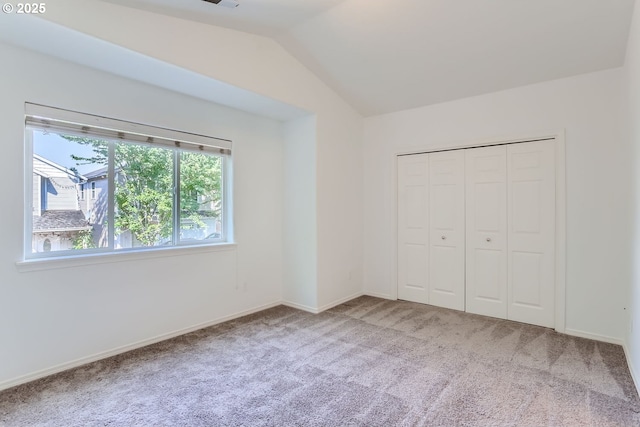 unfurnished bedroom featuring a closet, vaulted ceiling, and carpet