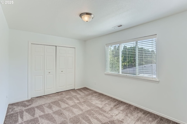 unfurnished bedroom with light colored carpet and a closet