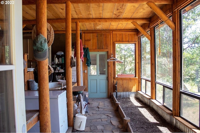 unfurnished sunroom featuring vaulted ceiling with beams