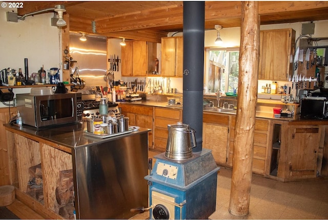 kitchen featuring beam ceiling, sink, and light tile floors