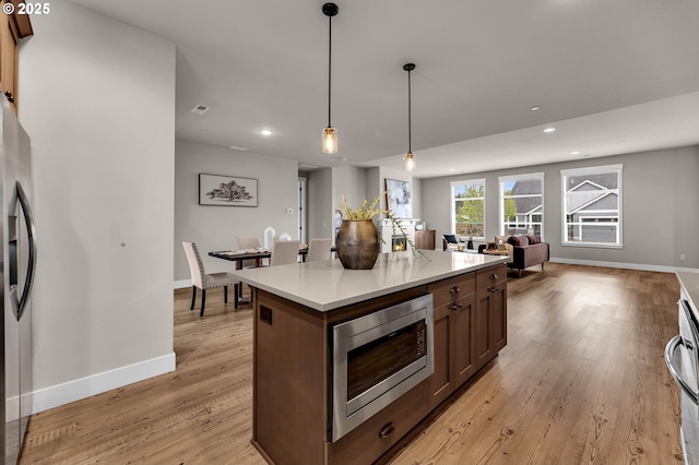 5719 N 87th Ave, Camas, WA 98607 - kitchen featuring appliances with stainless steel finishes, light wood finished floors, baseboards, open floor plan, and light countertops