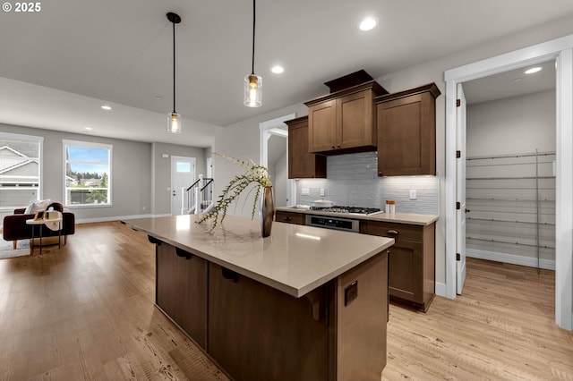 5719 N 87th Ave, Camas, WA 98607 - kitchen with baseboards, light wood finished floors, tasteful backsplash, light countertops, and a center island