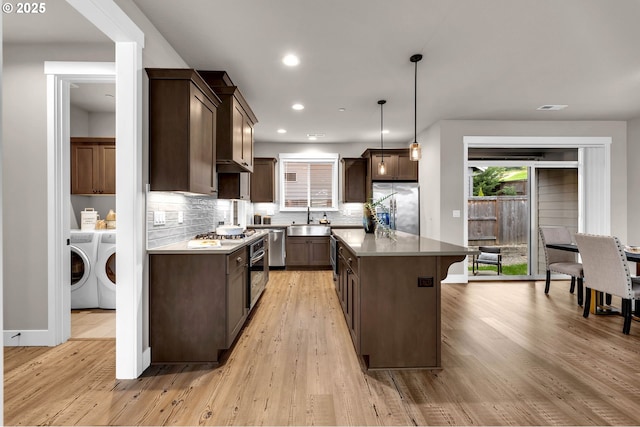 5719 N 87th Ave, Camas, WA 98607 - kitchen featuring stainless steel appliances, a sink, washing machine and dryer, dark brown cabinets, and backsplash
