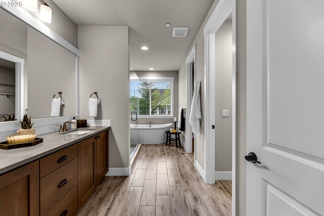 5719 N 87th Ave, Camas, WA 98607 - full bath with vanity, a freestanding tub, wood finished floors, baseboards, and recessed lighting