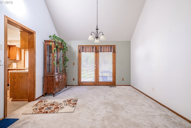 interior space featuring a chandelier, french doors, light colored carpet, and lofted ceiling