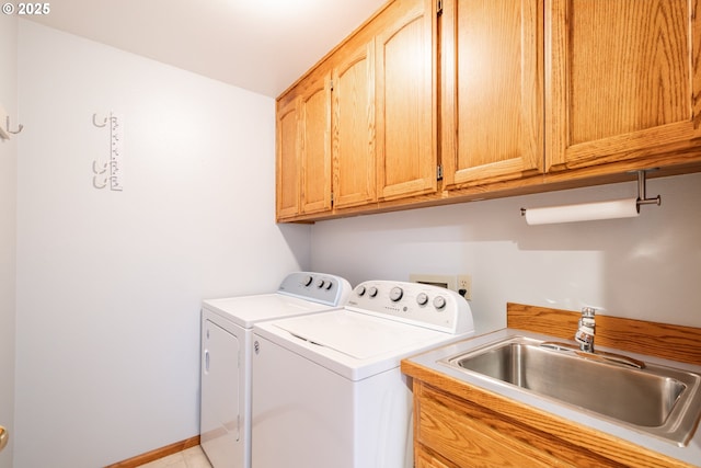 clothes washing area with cabinets, sink, and washing machine and clothes dryer