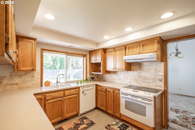 kitchen with a tray ceiling, sink, white appliances, and decorative backsplash