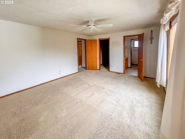 unfurnished bedroom with ensuite bathroom, a textured ceiling, ceiling fan, and light colored carpet