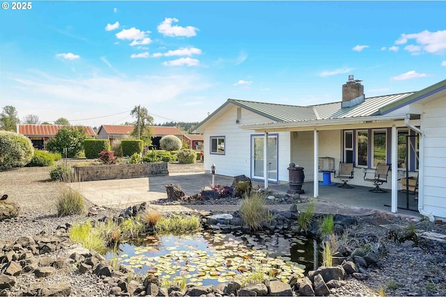 41108/41100 Oupor Dr, Scio, OR 97374 - back of house with a standing seam roof, a chimney, a garden pond, metal roof, and covered porch