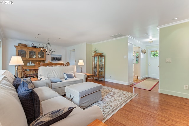 living room featuring crown molding, a notable chandelier, and light wood-style flooring