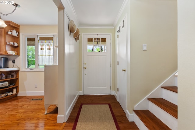 doorway with baseboards, ornamental molding, wood finished floors, and stairway