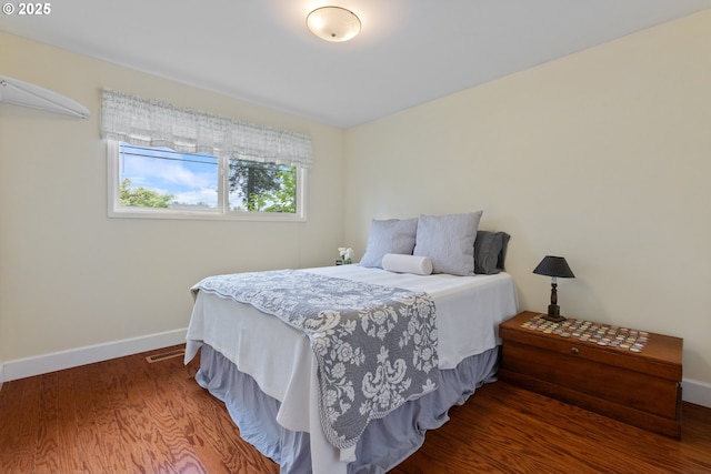 bedroom with baseboards, visible vents, and wood finished floors