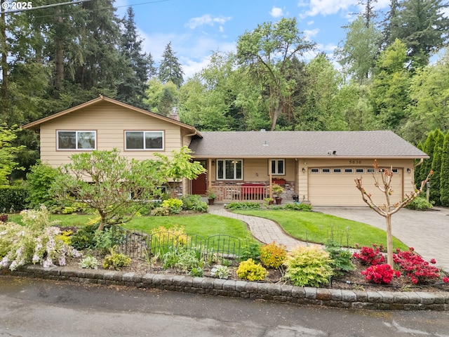 split level home featuring covered porch, an attached garage, driveway, and a front lawn