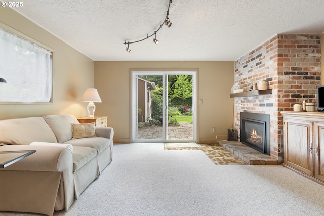 carpeted living room with a textured ceiling, baseboards, rail lighting, and a fireplace