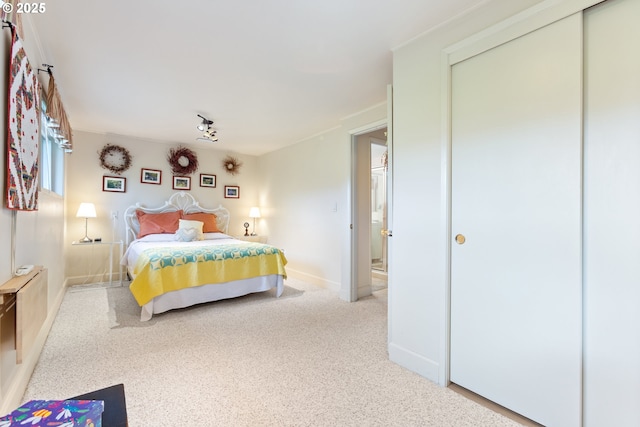 carpeted bedroom featuring baseboards and a closet