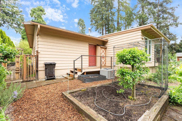 back of property featuring cooling unit and a garden