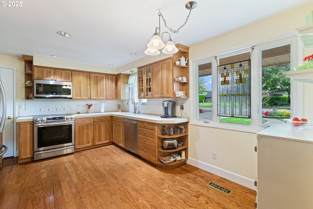 kitchen with appliances with stainless steel finishes, open shelves, light wood-style flooring, and brown cabinetry