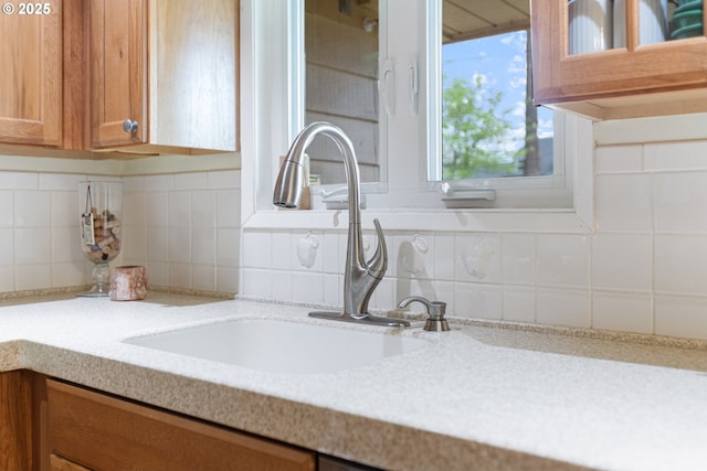 details featuring a sink, decorative backsplash, light stone countertops, and brown cabinets