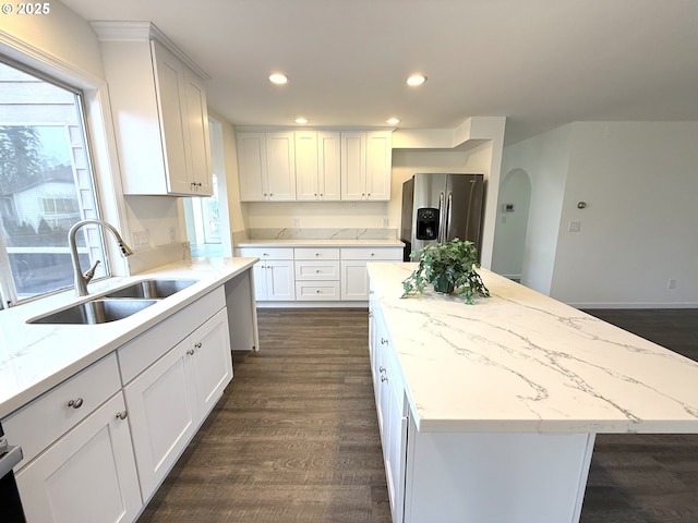 kitchen with a center island, sink, white cabinets, and stainless steel fridge with ice dispenser