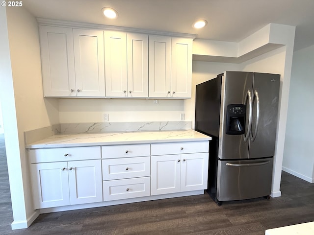 kitchen with white cabinetry, dark hardwood / wood-style flooring, stainless steel fridge, and light stone countertops