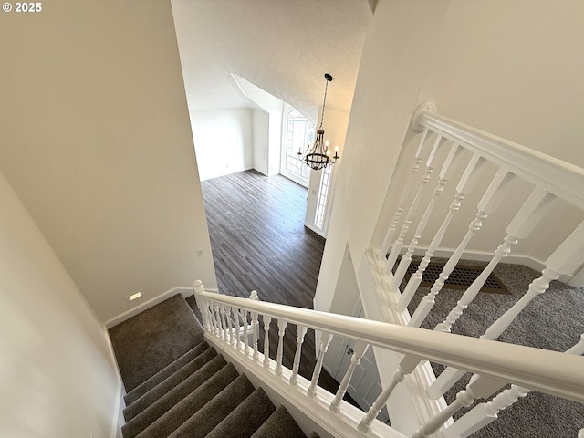 stairway featuring hardwood / wood-style flooring, lofted ceiling, and a notable chandelier