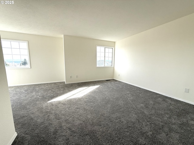 unfurnished room featuring a textured ceiling and dark carpet