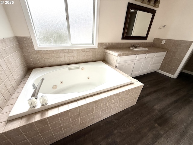 bathroom featuring hardwood / wood-style floors, vanity, and a relaxing tiled tub