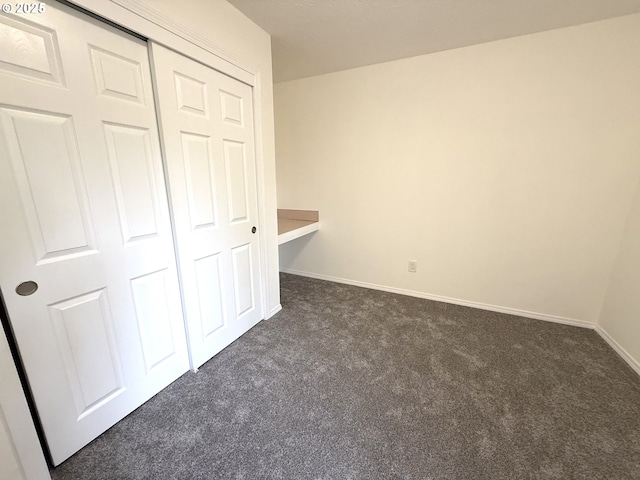 unfurnished bedroom featuring dark carpet and a closet